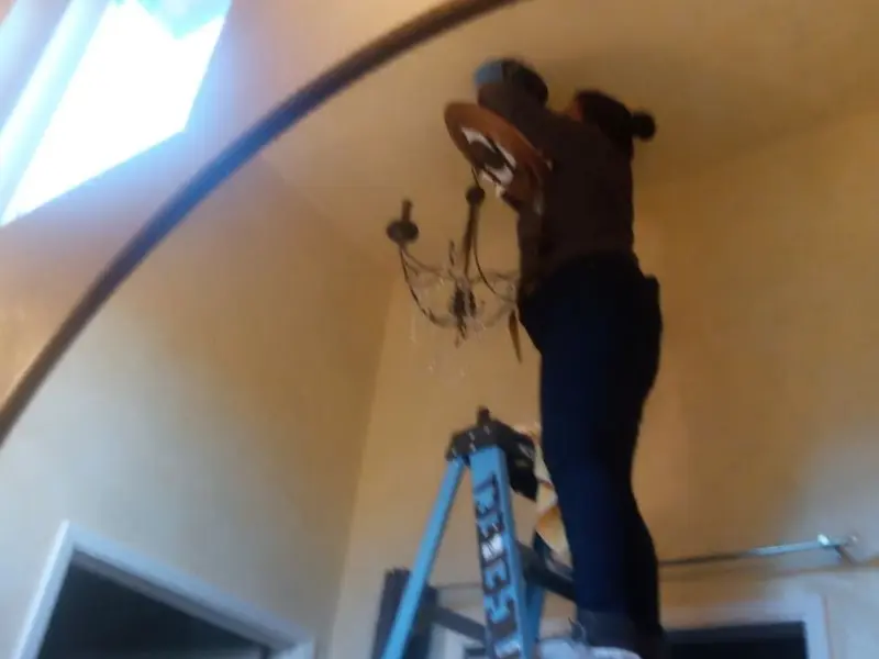 Electrician installing a chandelier in a Gardiner residence